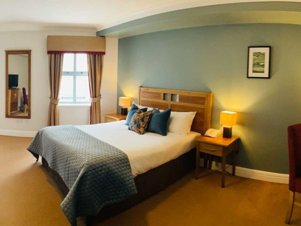 Cozy bedroom with a double bed, blue accents, and warm lighting.
